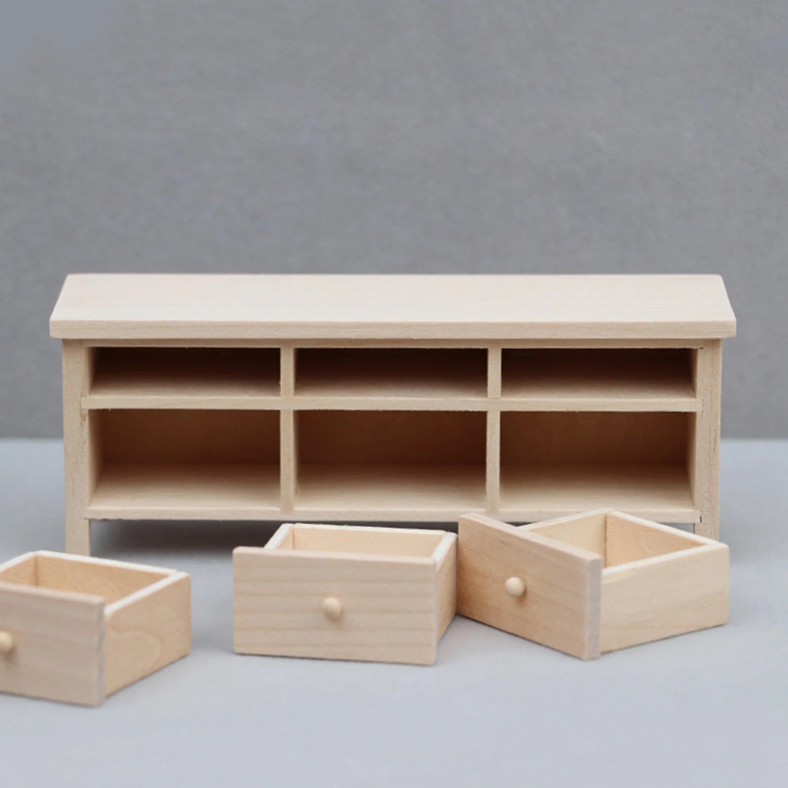 Wooden toy shelf with multiple compartments and drawers on a gray background