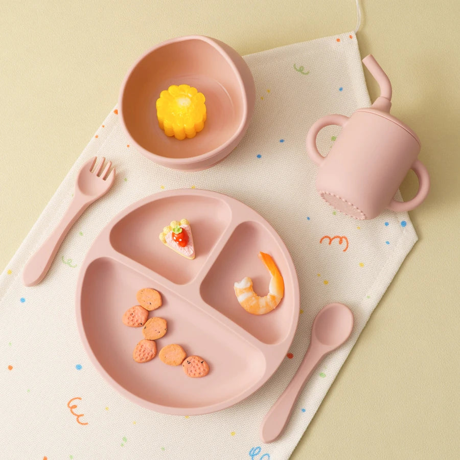 Light pink divided plate, bowl and straw cup with food on a table