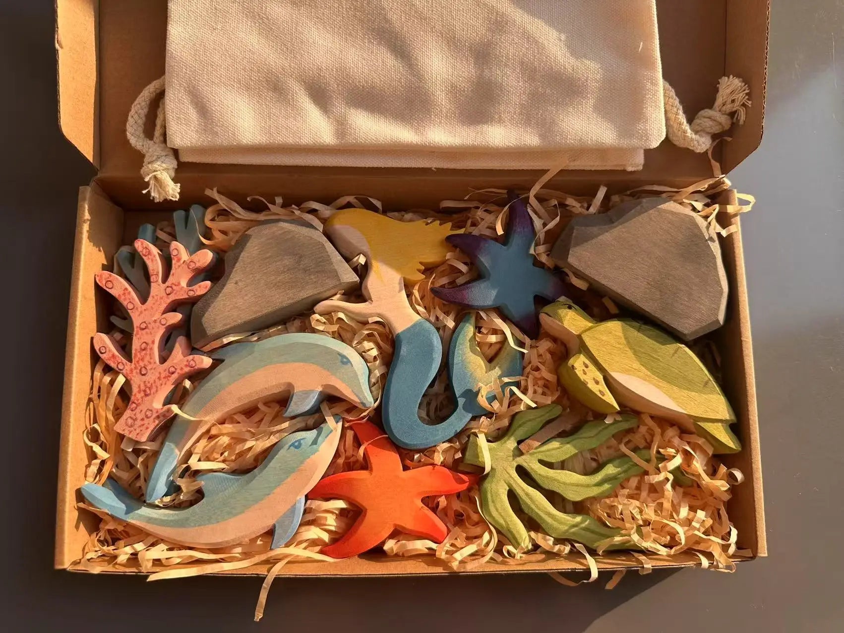 Box of colorful wooden sea creature toys on a dark surface