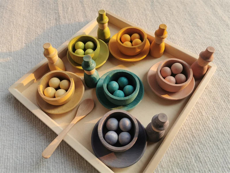 Colorful wooden toy set with bowls and a spoon on a light surface
