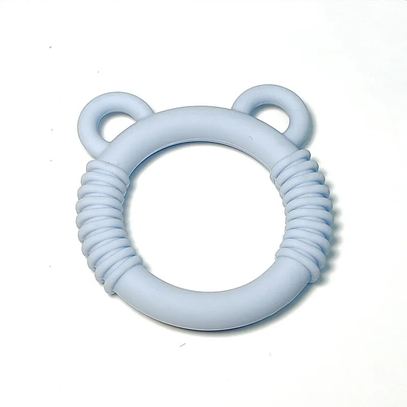 A light blue silicone baby teether with a circular ring design, textured ridges, and two small loop handles resembling ears, shown on a plain white background.