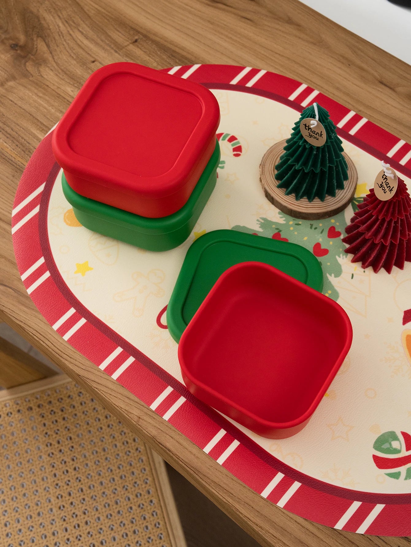Red and green square silicone snack containers with lids on a Christmas placemat