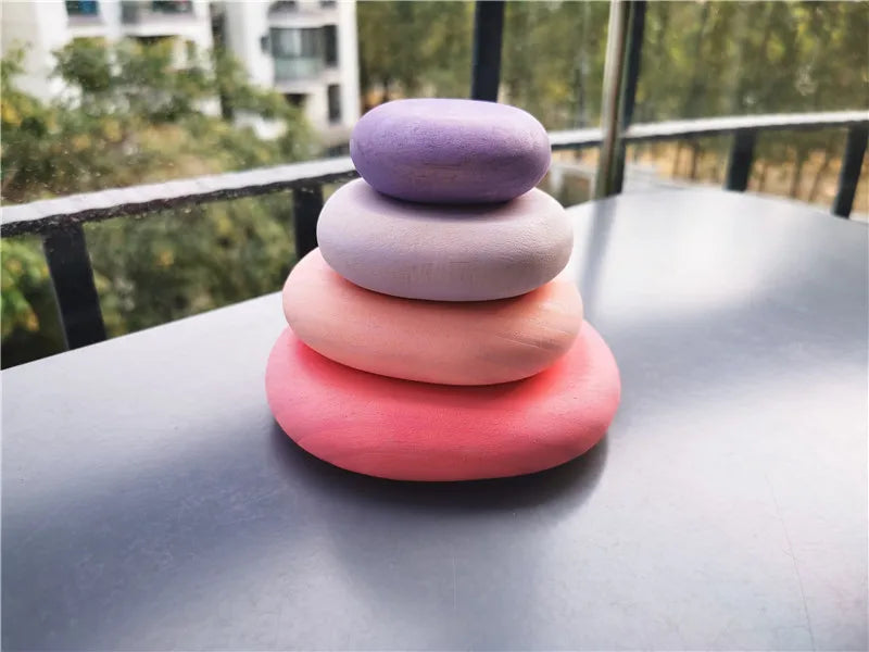 Stack of colorful stones on a reflective surface with a blurred outdoor background