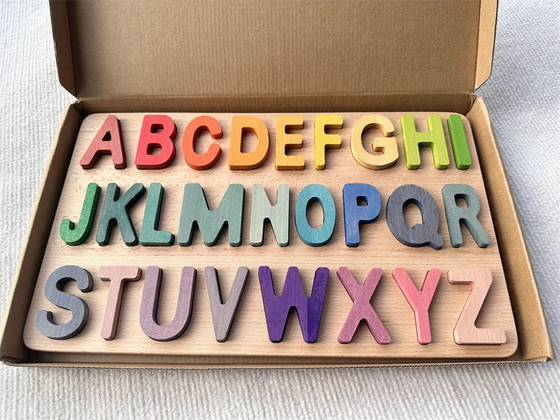 Colorful wooden alphabet letters in a cardboard box on a light background