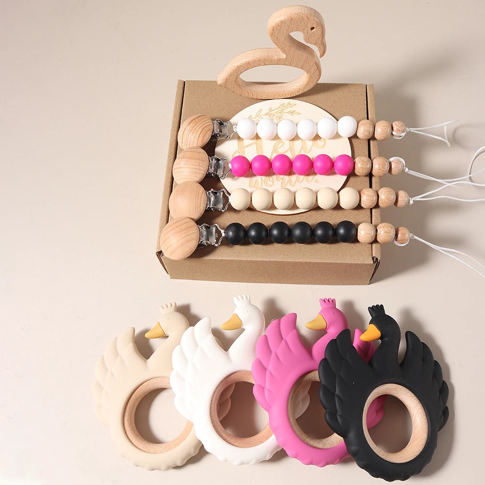 Set of wooden and silicone baby teething toys with a cardboard box on a beige background