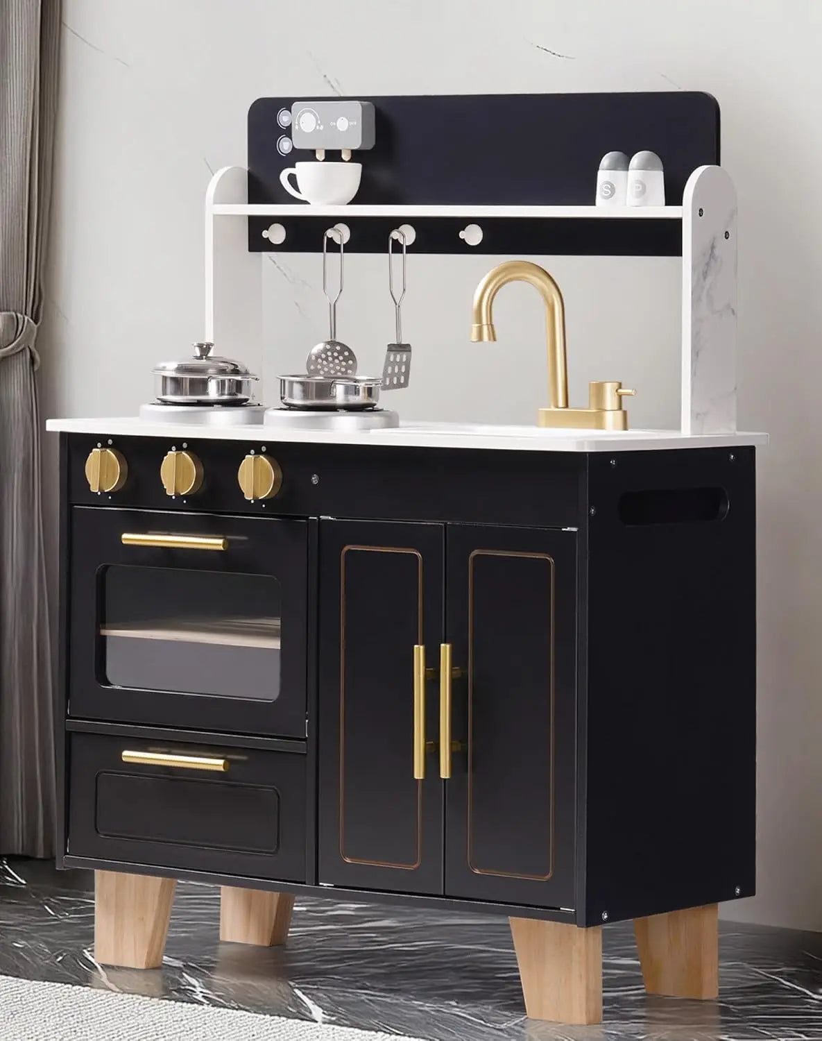 Black play kitchen set with gold accents on a gray floor.