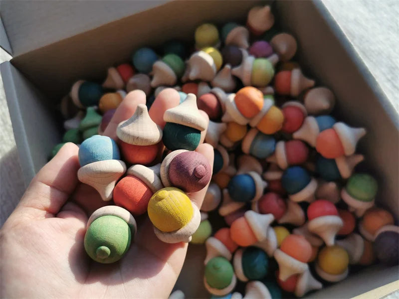Colorful acorns held in a hand with a box of more cookies in the background