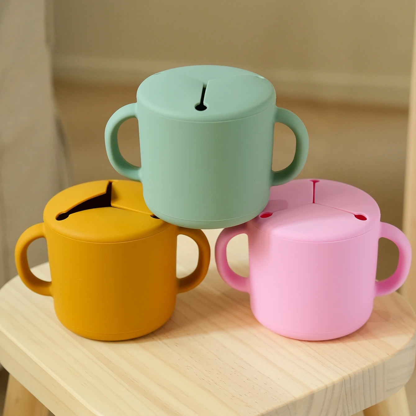 Three silicone snack cups stacked on a wooden table
