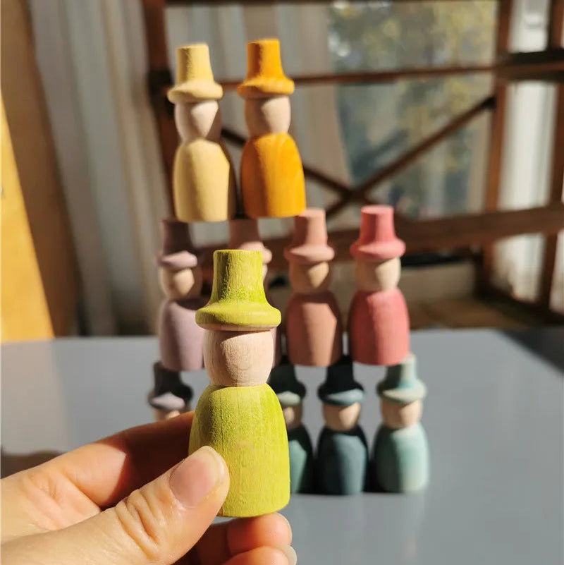 Colorful wooden peg dolls on a stand with a hand holding a green doll.