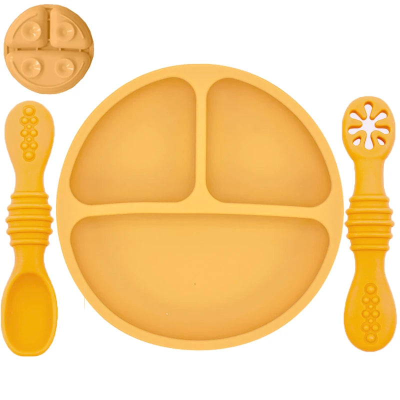 Yellow silicone plate with divided sections, spoon, and fork on a white background