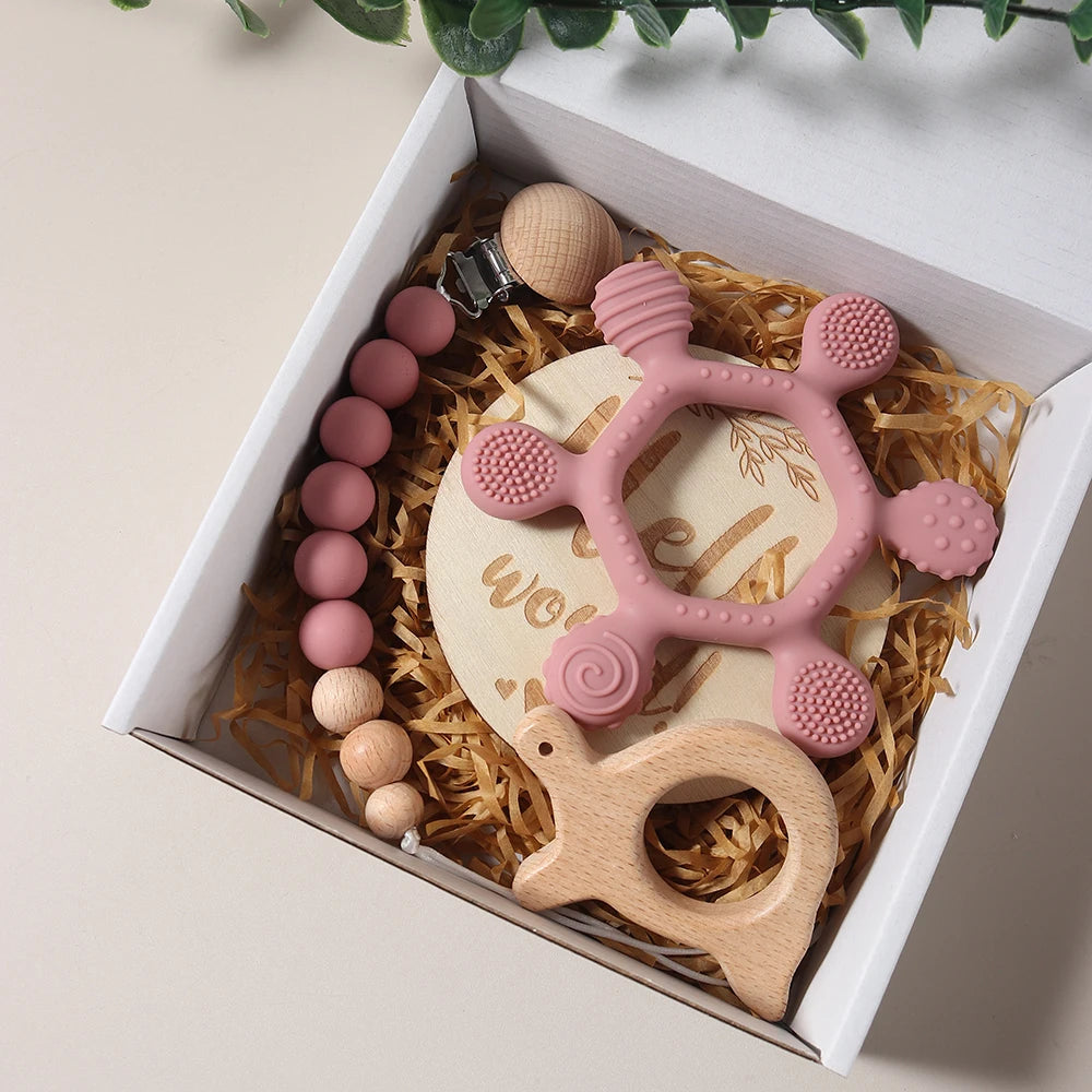 Baby teething toy set with pink and wooden elements in a box.