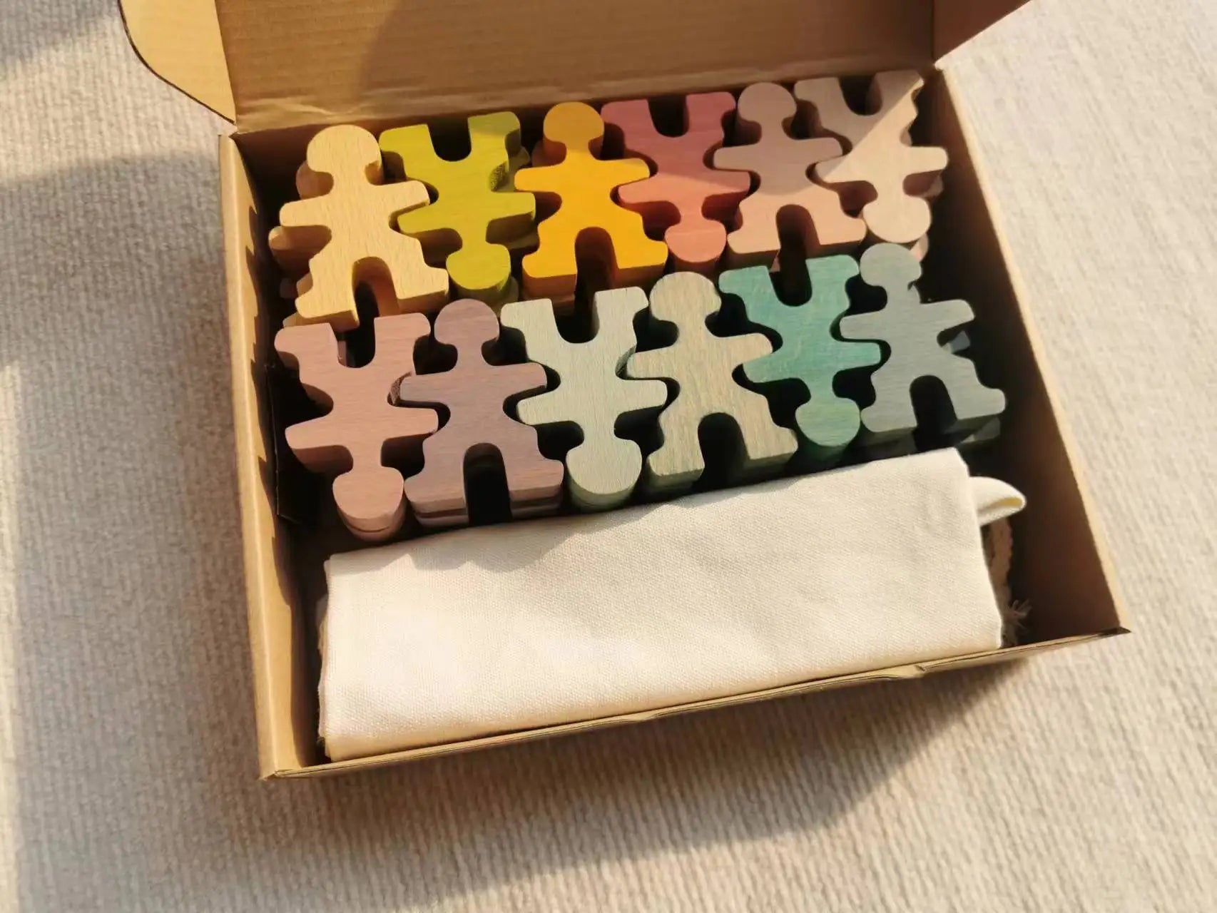 Set of colorful wooden puzzle pieces in a box with a cloth inside.