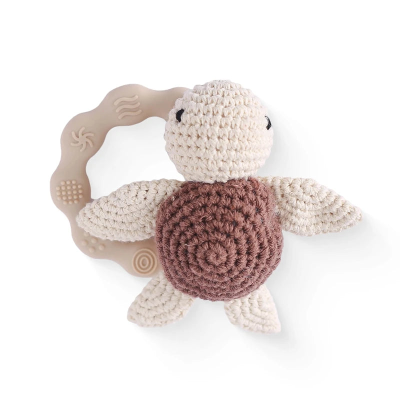 Crocheted turtle rattle with a beige handle on a white background