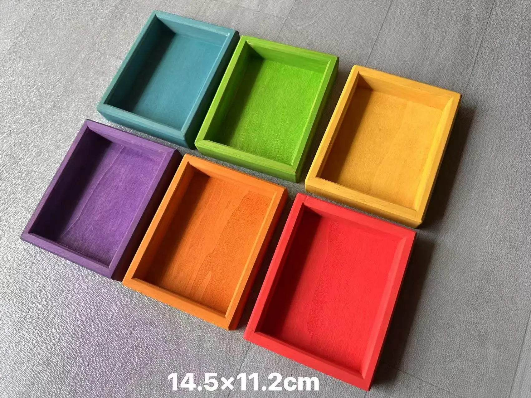 Set of six colorful rectangular trays on a gray surface