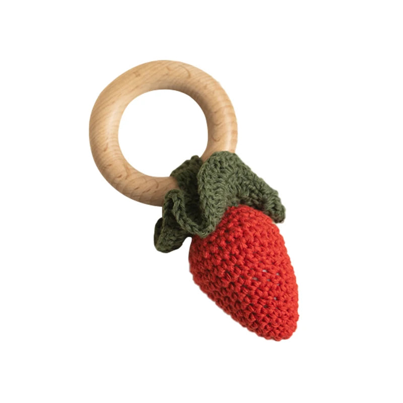 Wooden teething ring with a red and green crocheted strawberry on a white background
