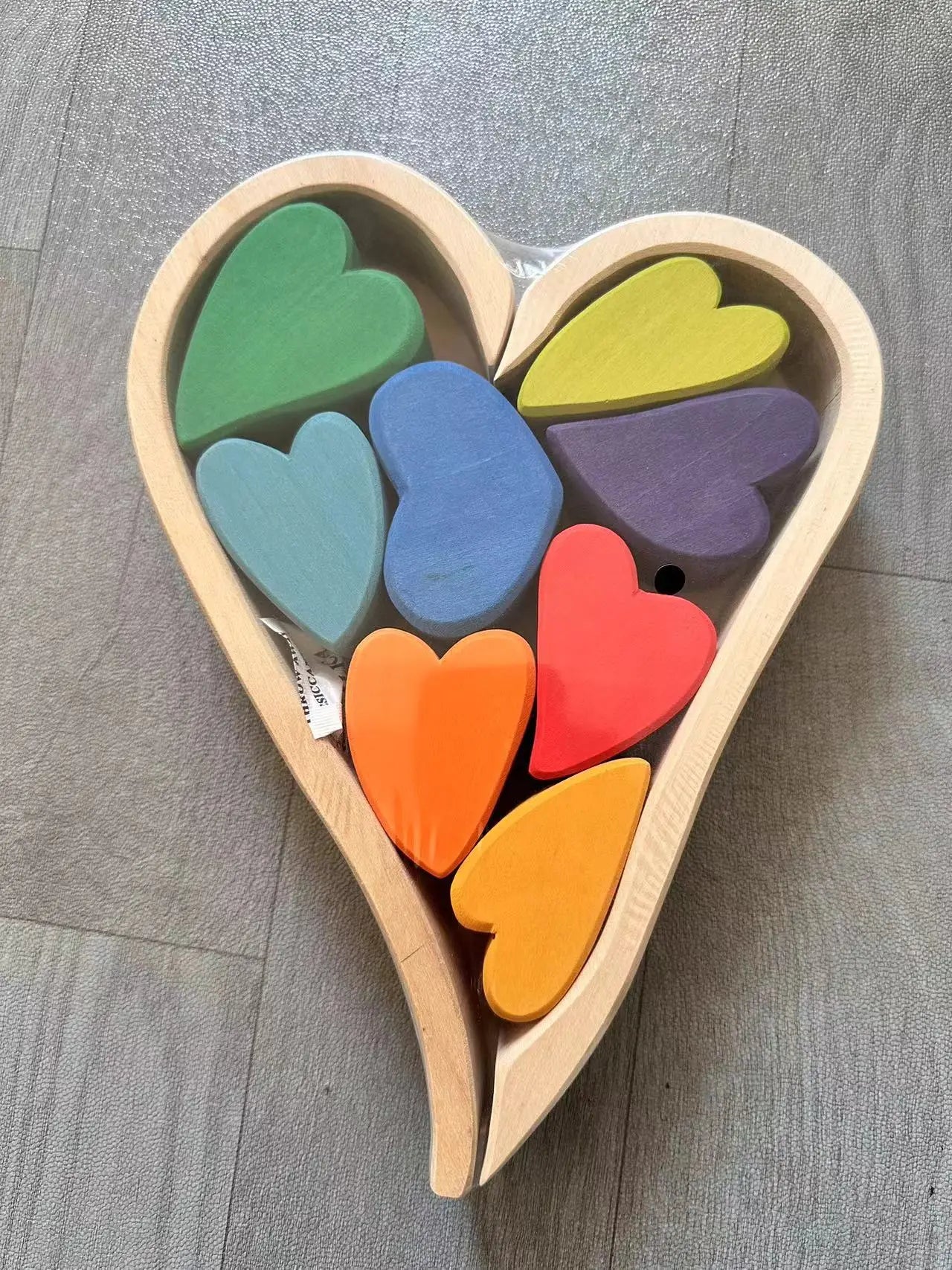 Heart-shaped wooden toy with colorful heart-shaped blocks on a gray surface