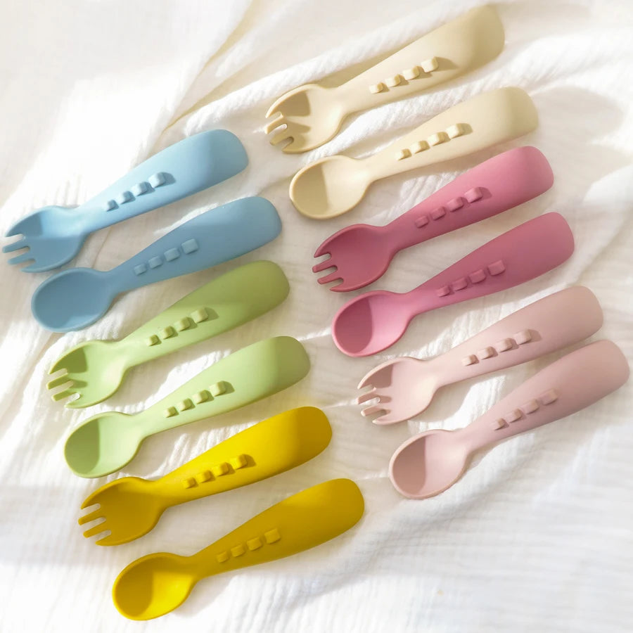 Silicone spoon and fork pairs laid out on a white cloth