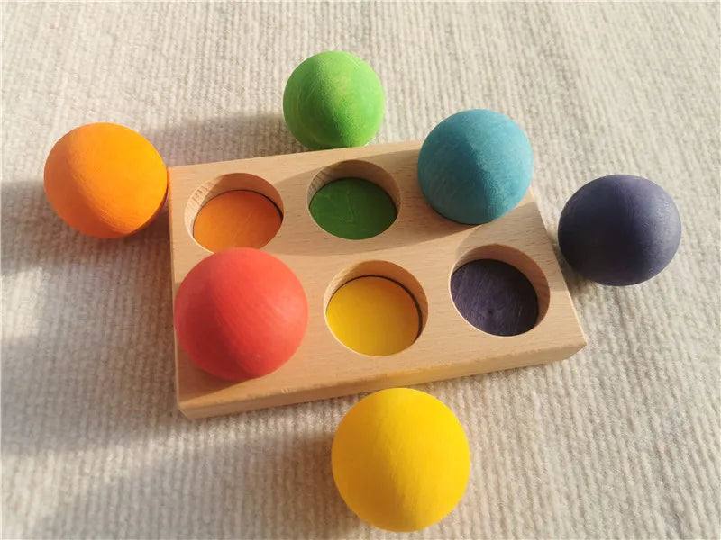Colorful wooden toy with compartments and matching colored balls on a textured surface