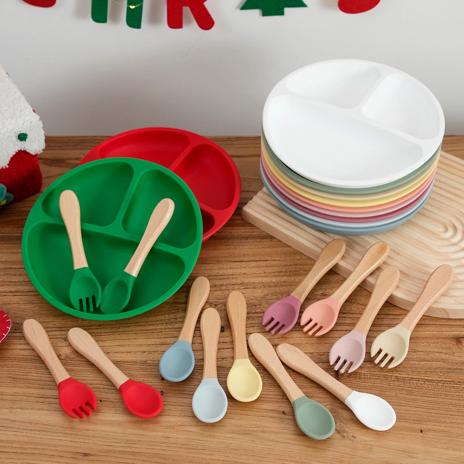 Red and green silicone divided suction plates with wooden handle spoons and forks and Christmas decor
