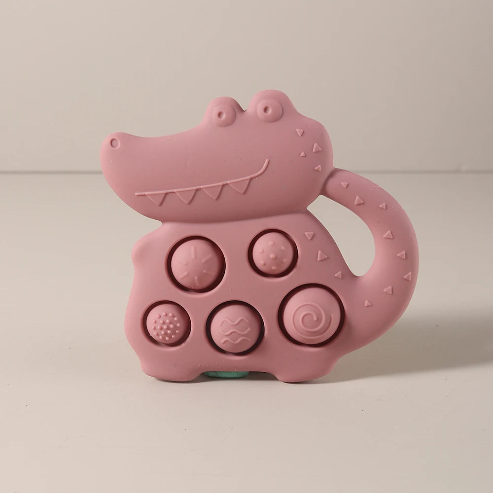 Pink alligator-shaped toy with textured buttons on a beige background