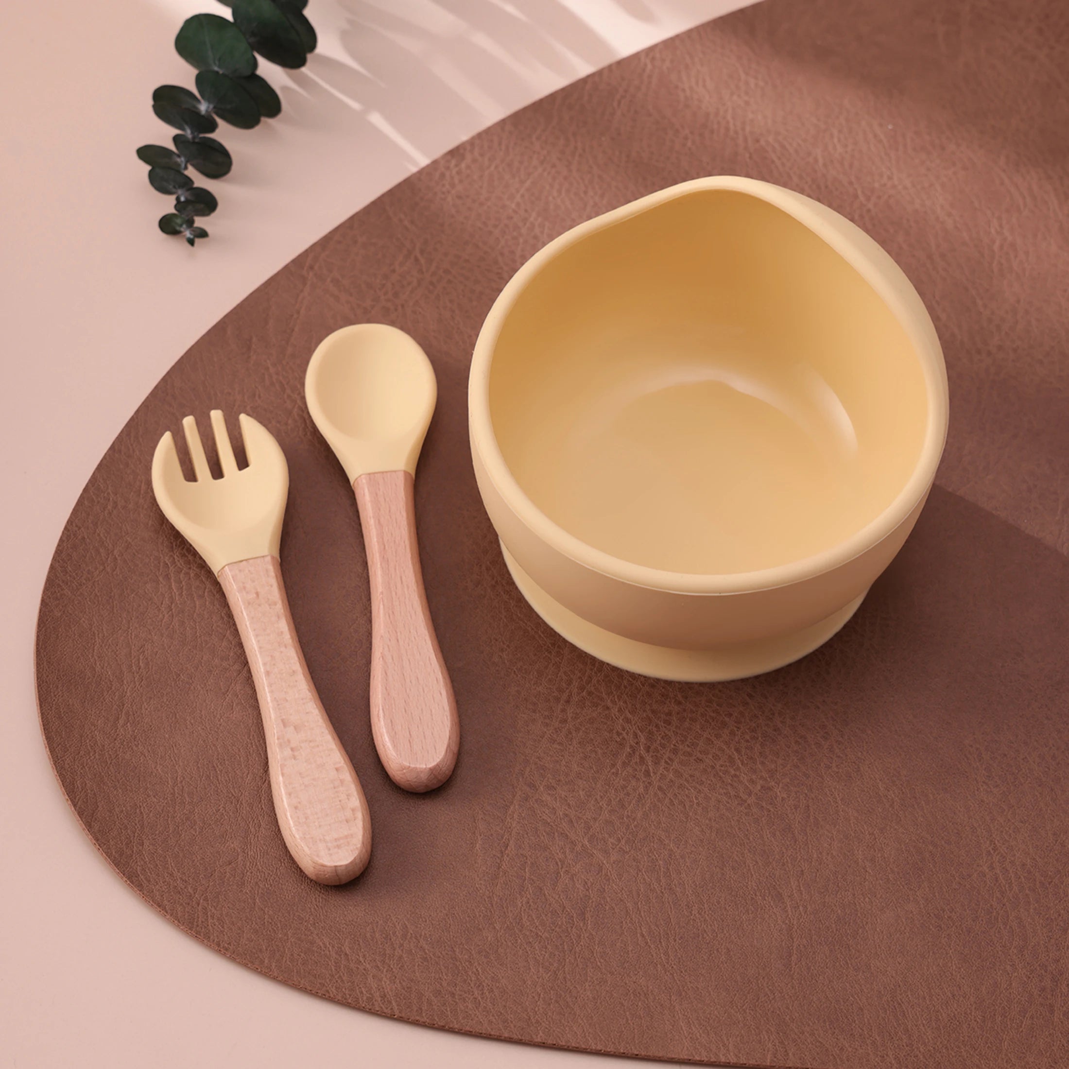 Light yellow suction bowl with wooden spoon and fork