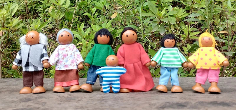 Set of toy figures in colorful clothing standing on a wooden surface with a natural background.
