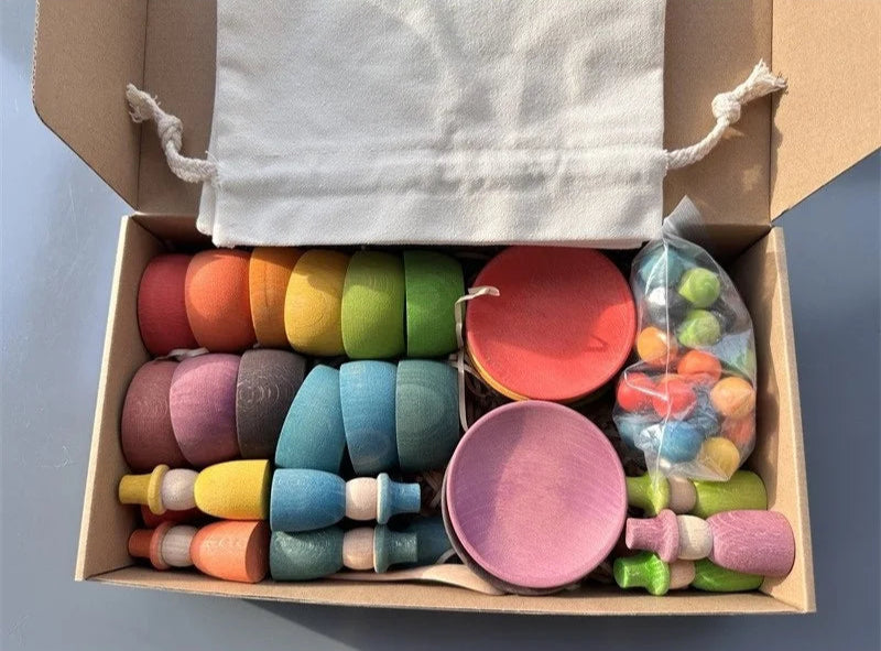 Colorful wooden toys in a box with a white drawstring bag.