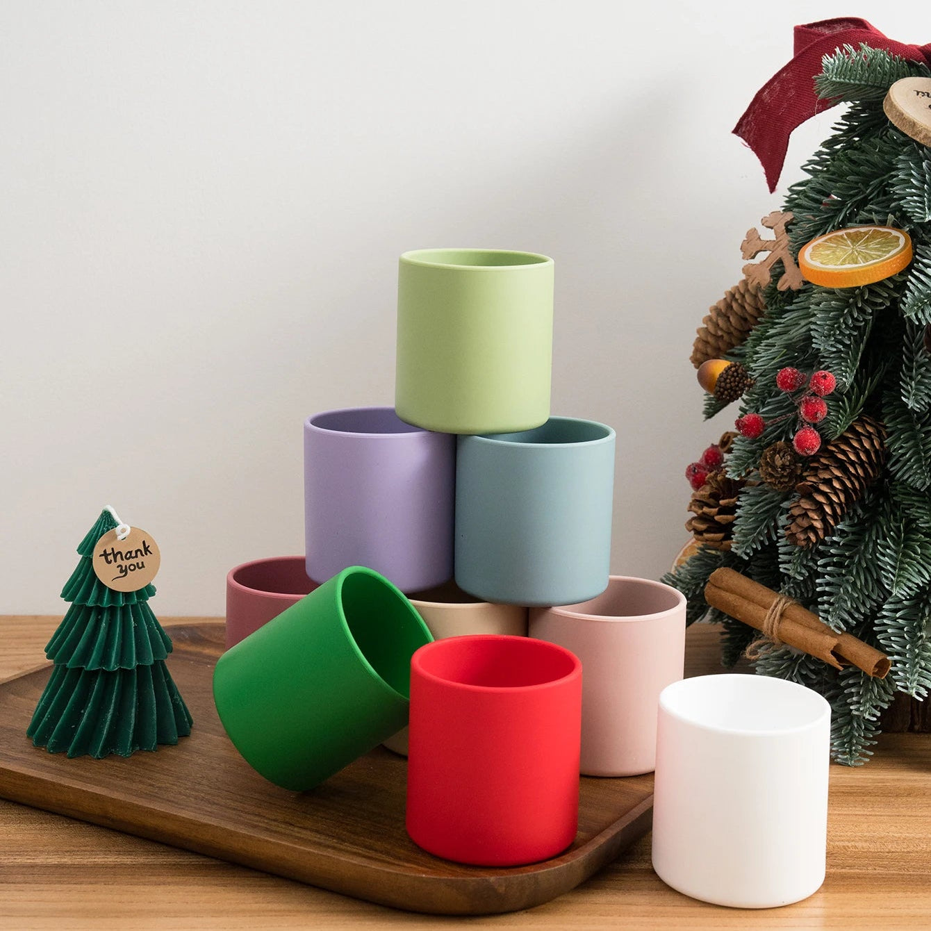 Silicone open training cups in red, green and pastel colors beside a Christmas tree