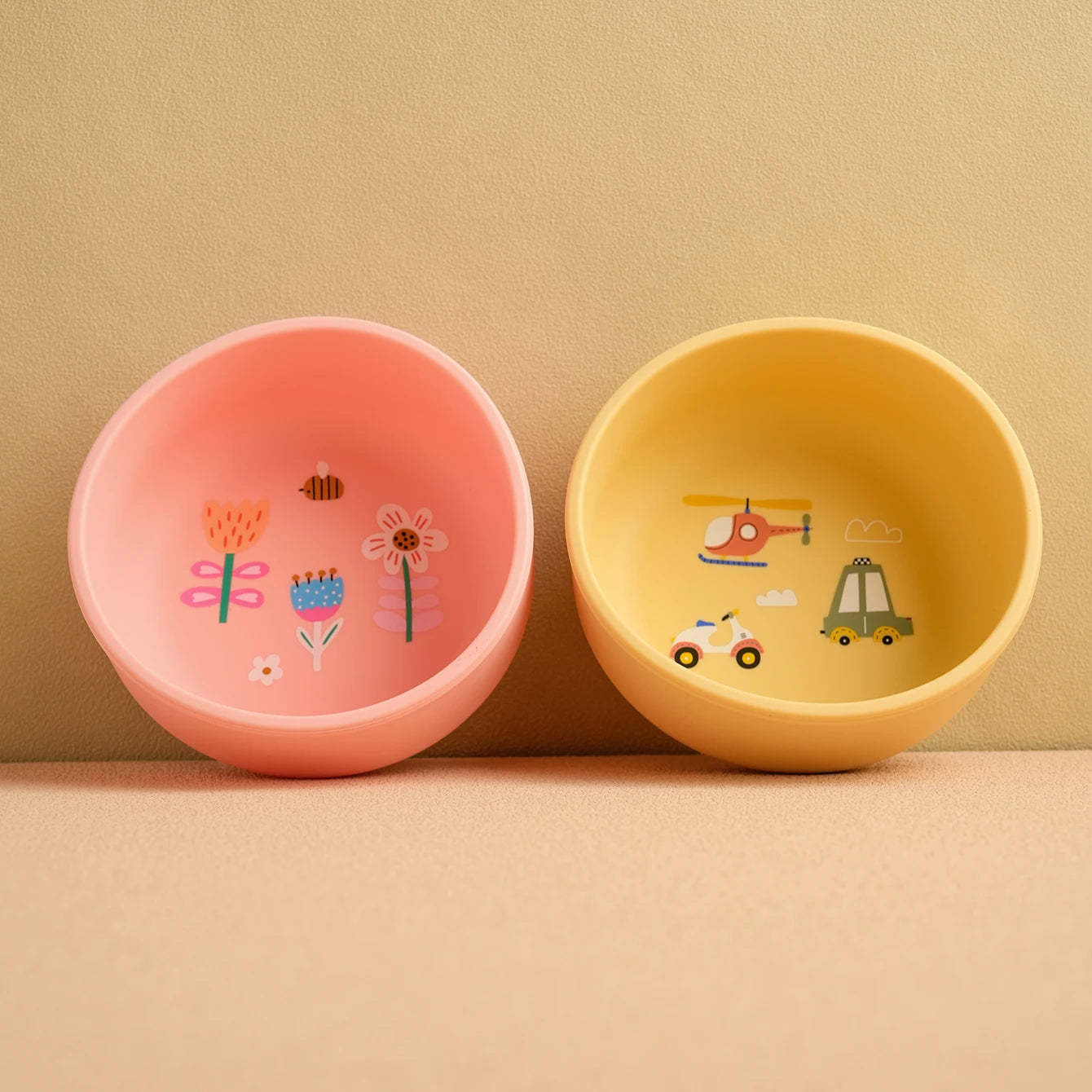 Pink flower and yellow helicopter print silicone bowls side by side