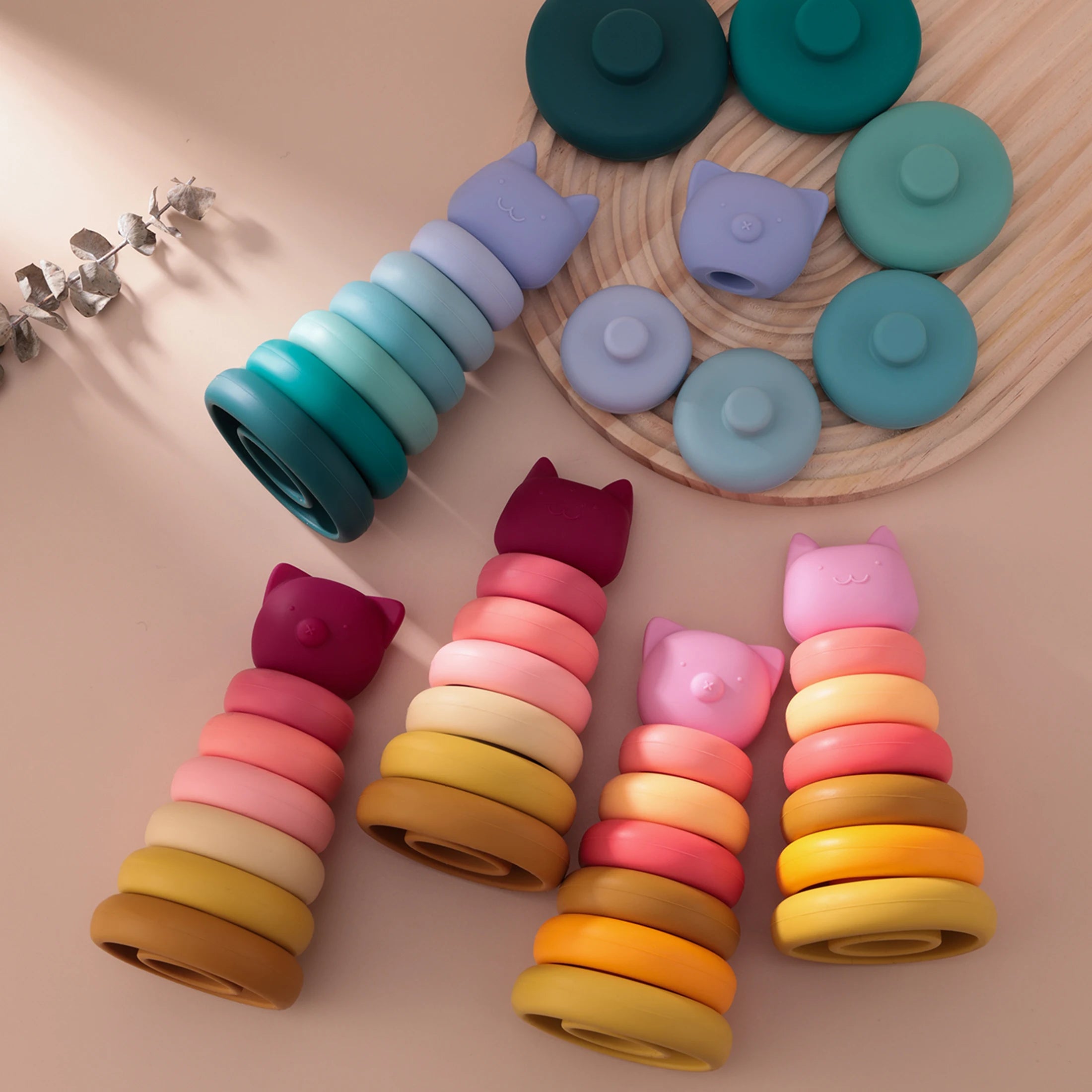 Colorful baby teething rings with cat-shaped ends on a wooden surface