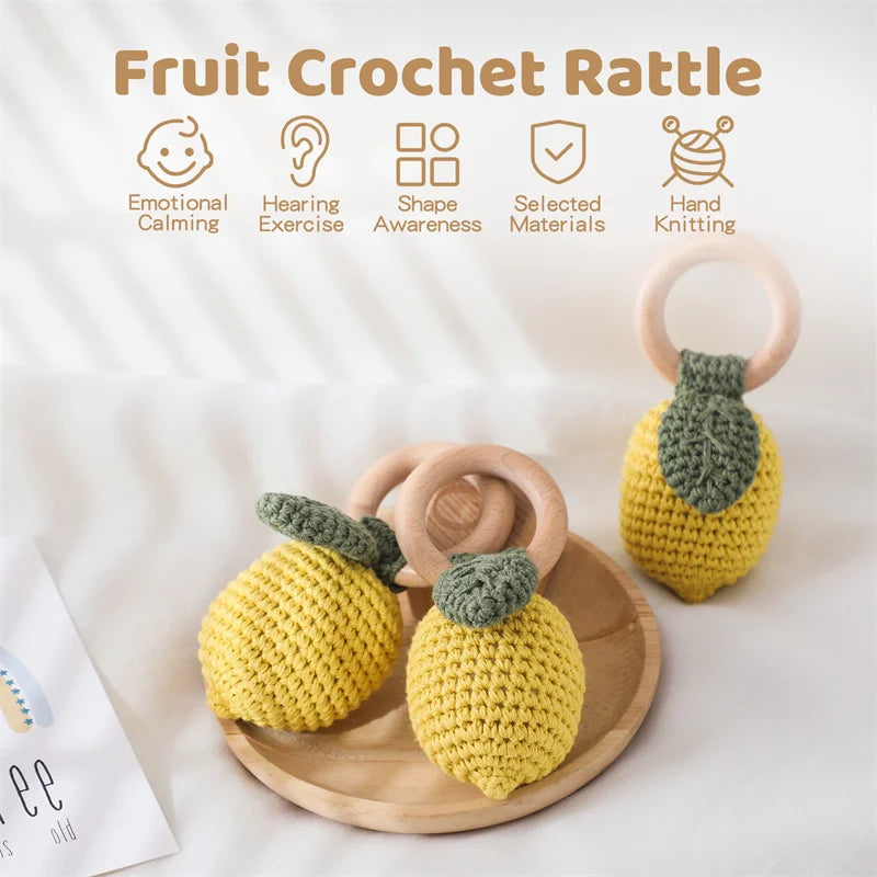 Crocheted fruit rattle with wooden rings on a white background