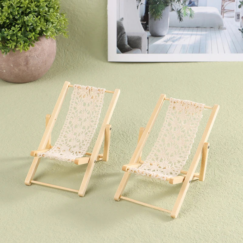 Two miniature wooden deck chairs with woven seats on a light green surface. Oliver & Company Montessori Toys