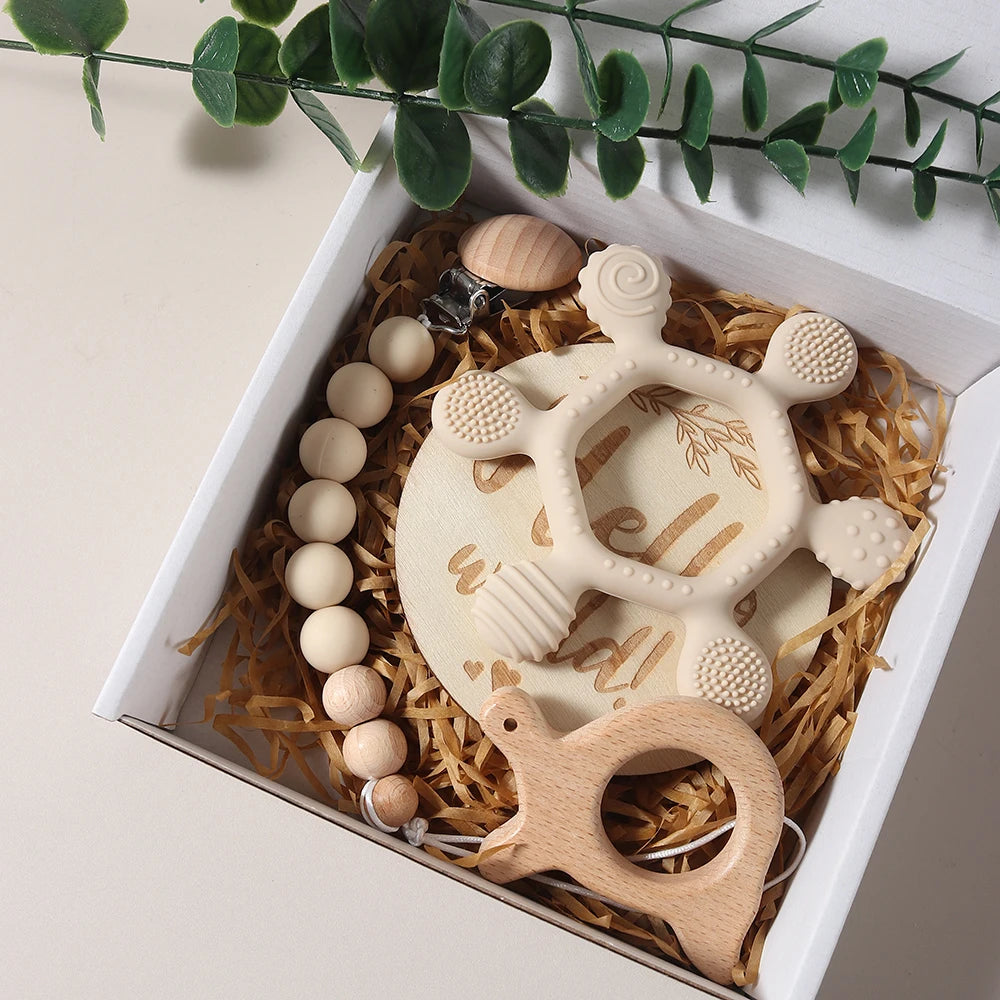 Teething toys and wooden beads in a decorative box with greenery.