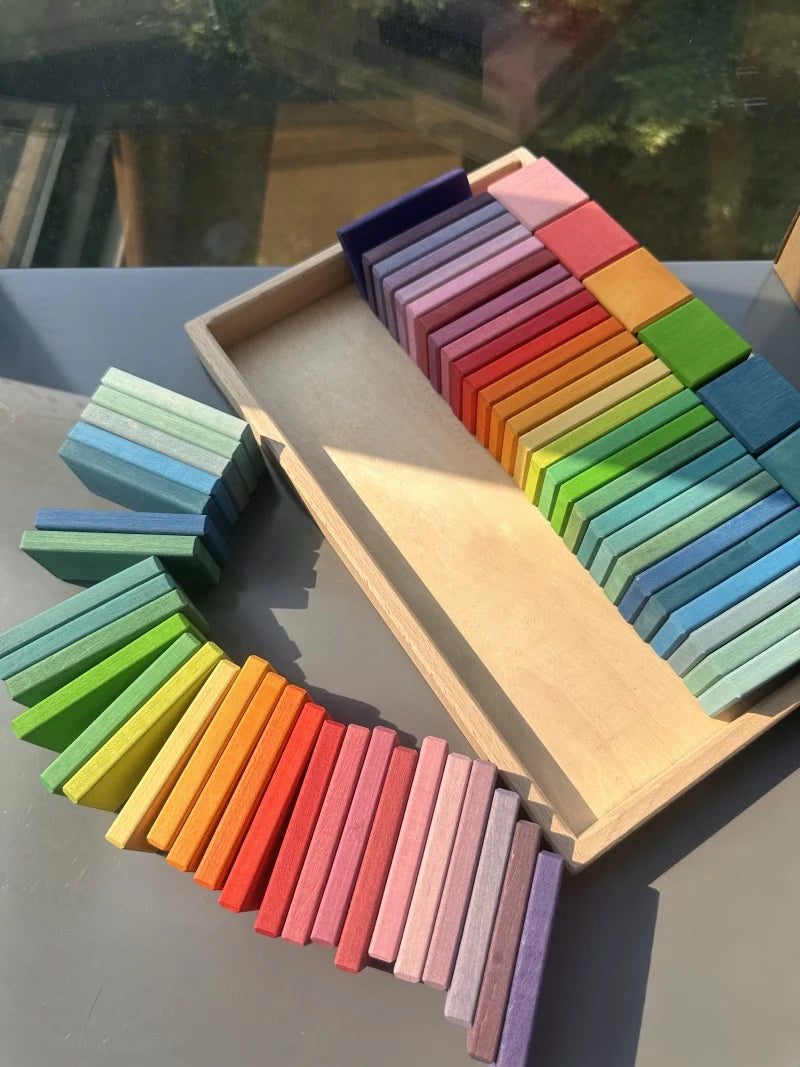 Colorful wooden blocks in a rainbow pattern on a gray surface.