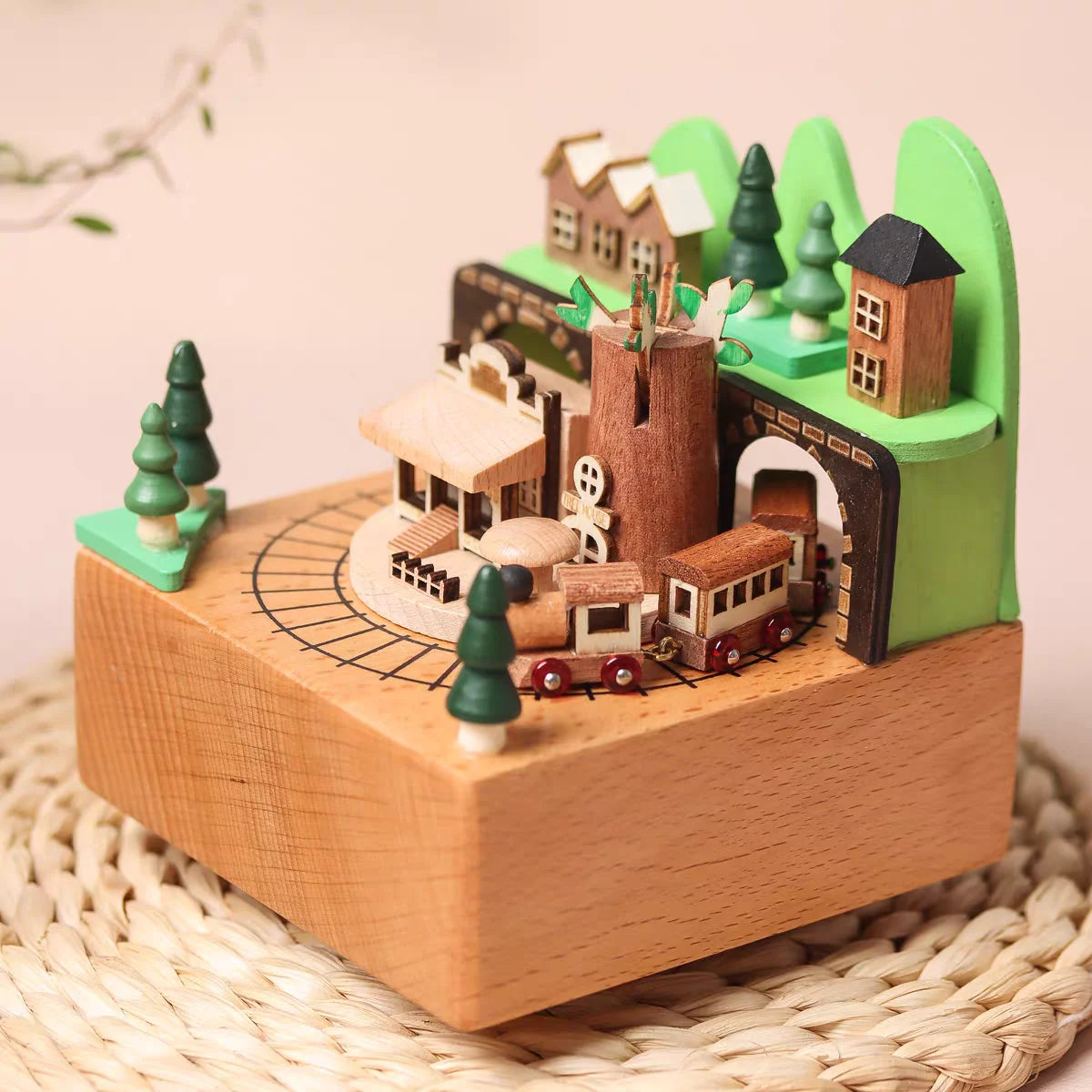 Wooden toy train set with buildings and trees on a woven surface