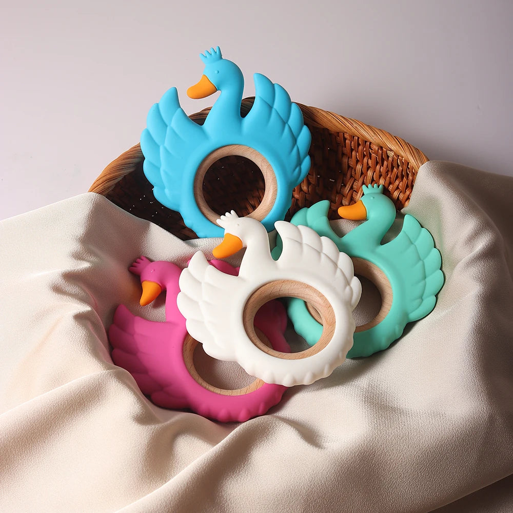 Set of colorful swan-shaped teething rings on a beige fabric background