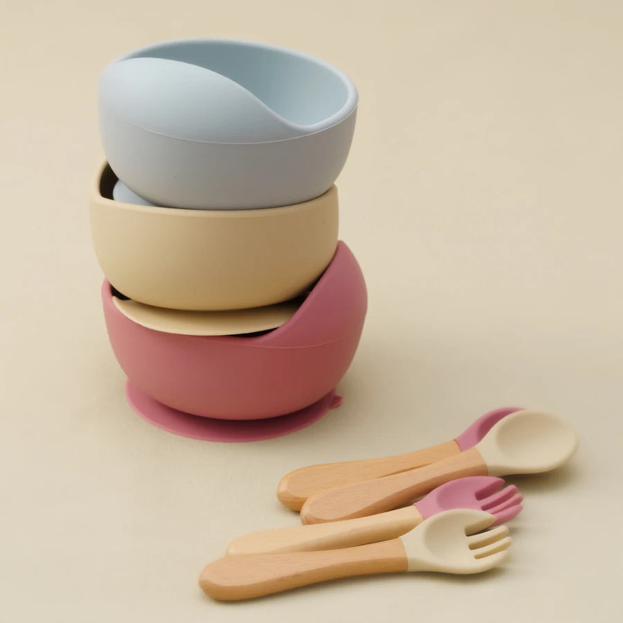 Stacked suction bowls in grey, cream and rose with wooden utensils