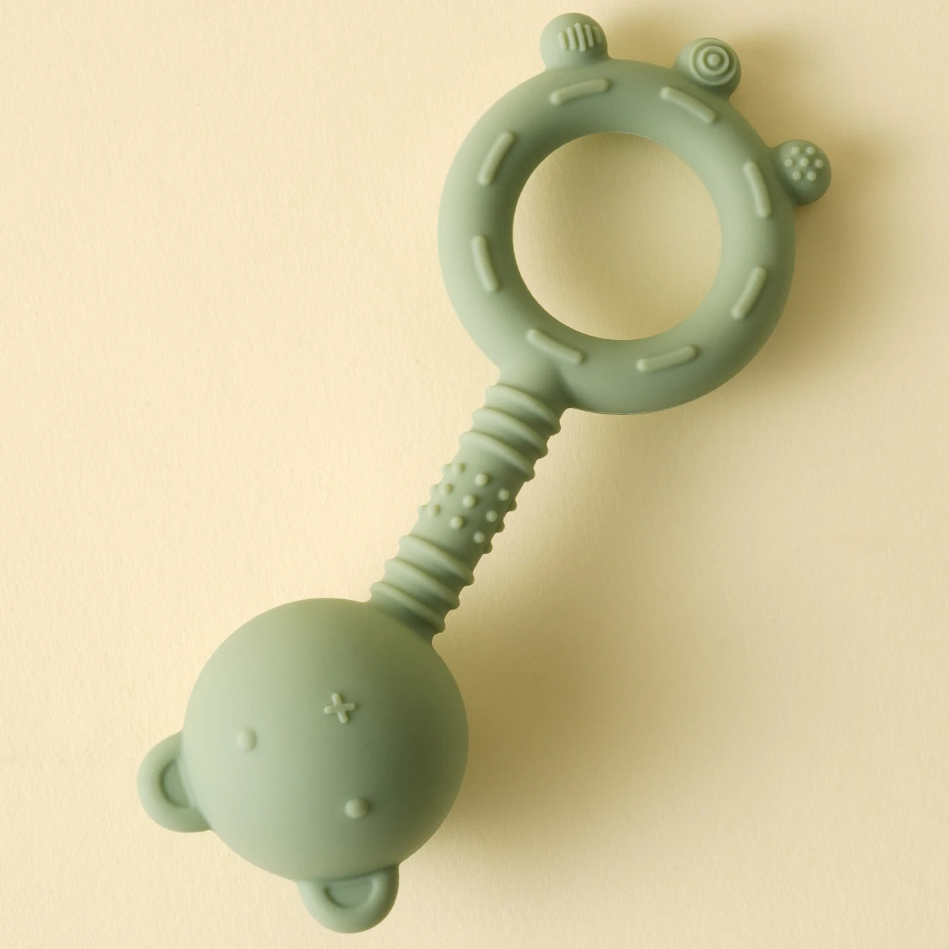 Green silicone teething ring on a beige background