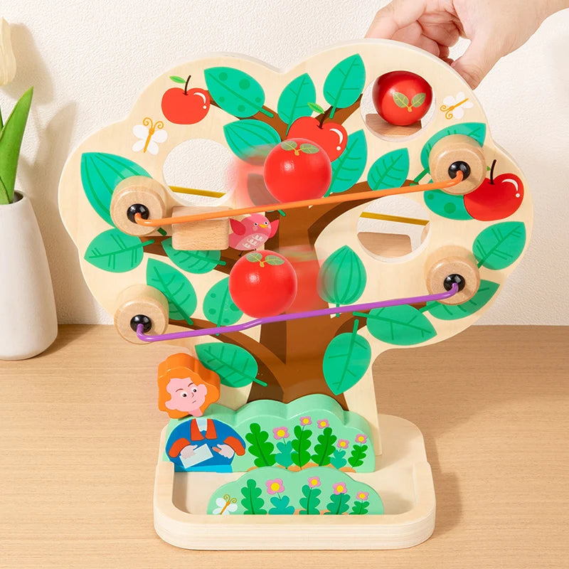Wooden toy with apples and a child figure on a wooden surface