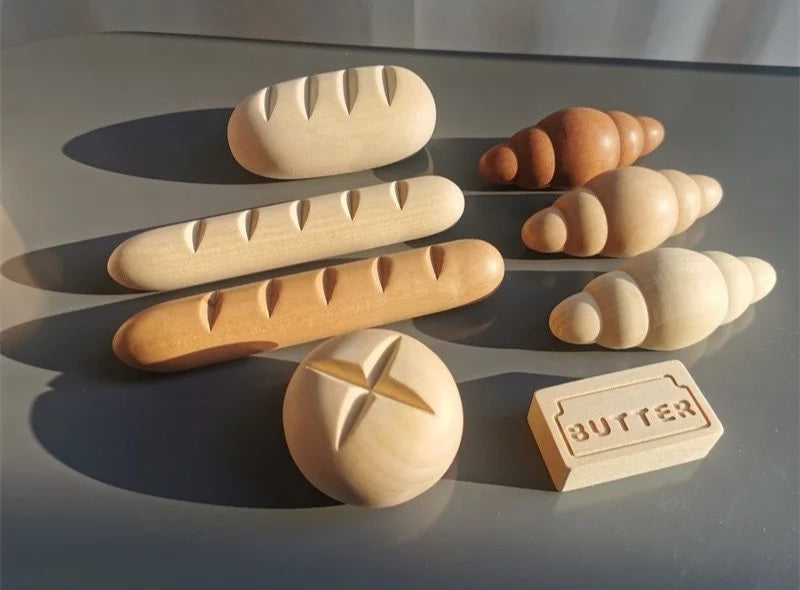 Wooden models of bread and a block labeled 'butter' on a reflective surface.