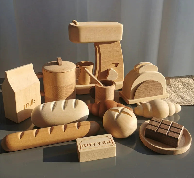 Collection of wooden food items including bread, milk carton, and chocolate on a reflective surface with a neutral background.