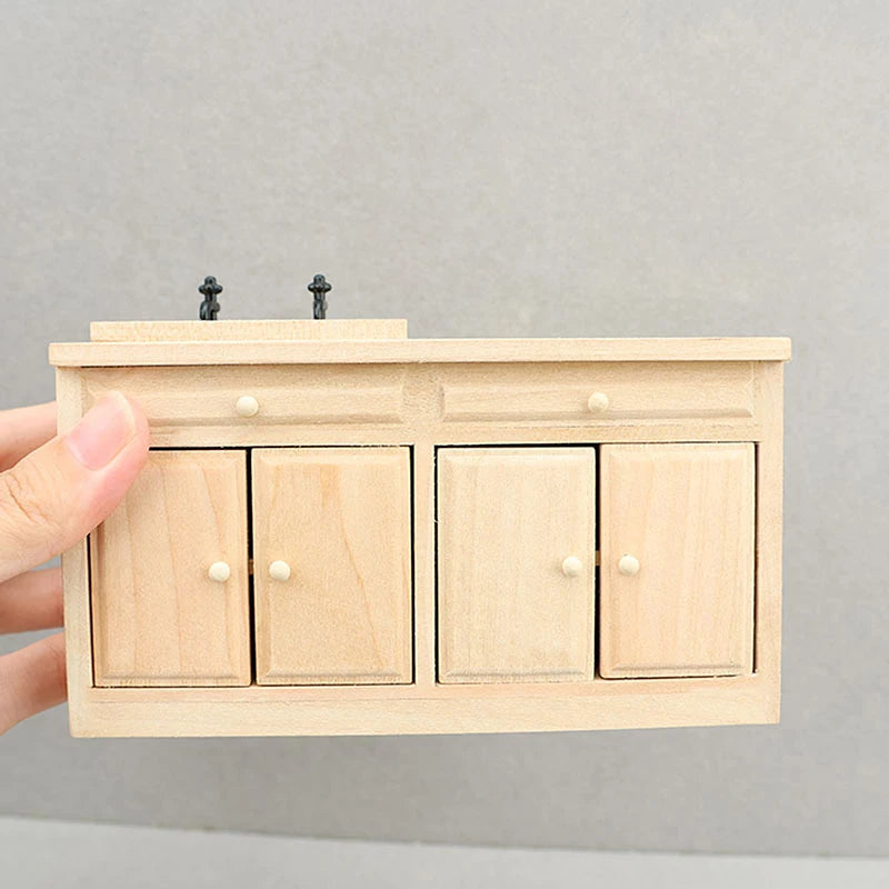 Hand holding a miniature wooden cabinet with doors against a gray background