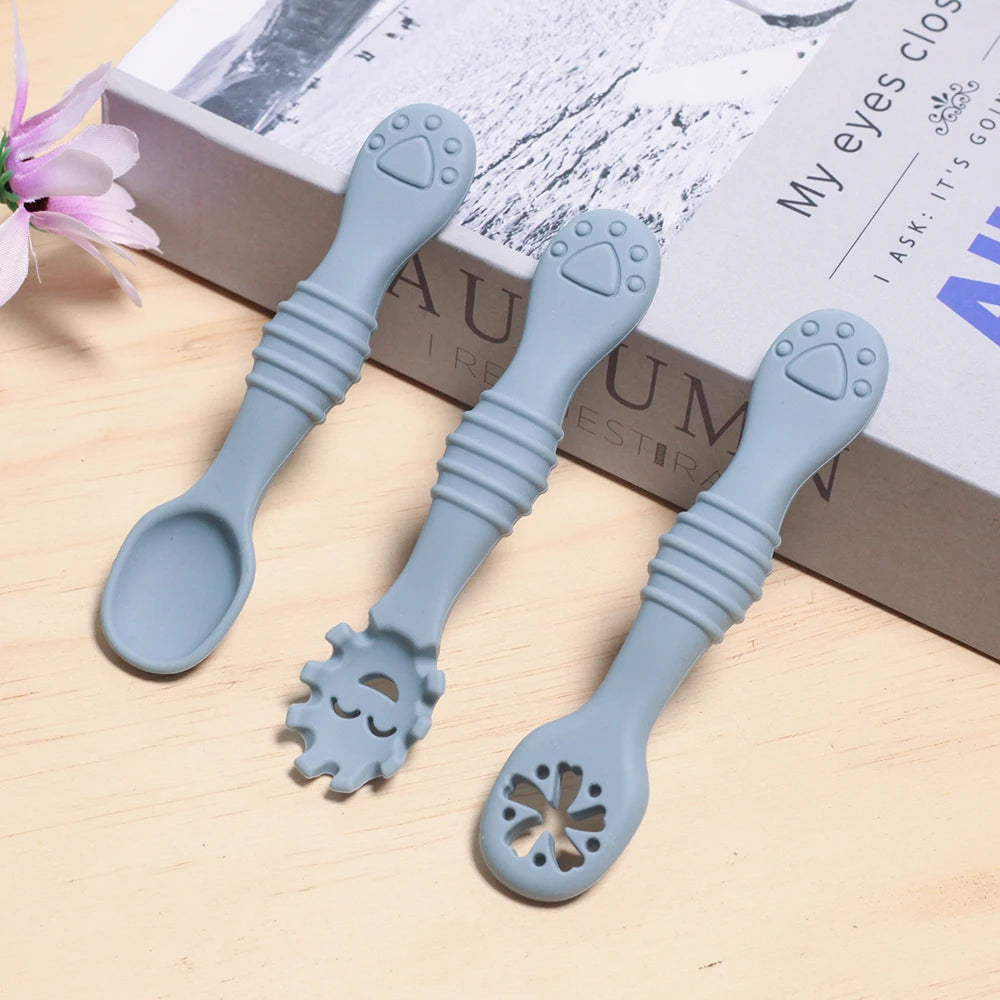 Three blue silicone utensils on a wooden surface with a book in the background.