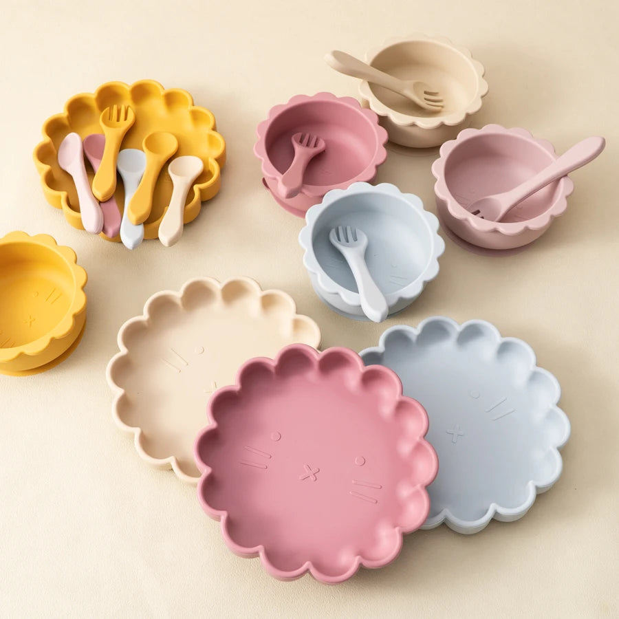 Set of colorful children's plates, bowls, and utensils on a beige background