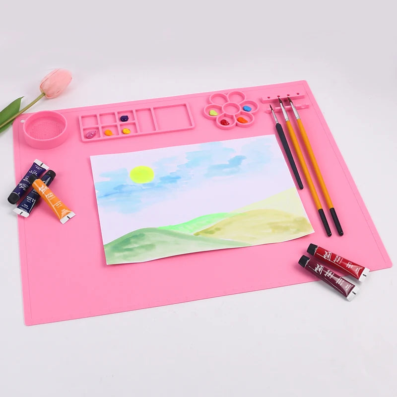 Pink art desk with painting supplies and a child's drawing of a landscape.