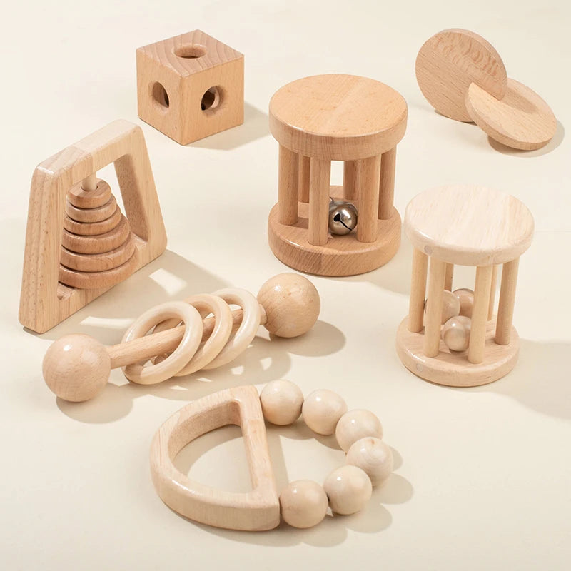 Set of wooden baby toys on a light backgrouMontessori Wooden Baby Rattle Set with Soft Sensory Book | Oliver Montessori Toysnd 