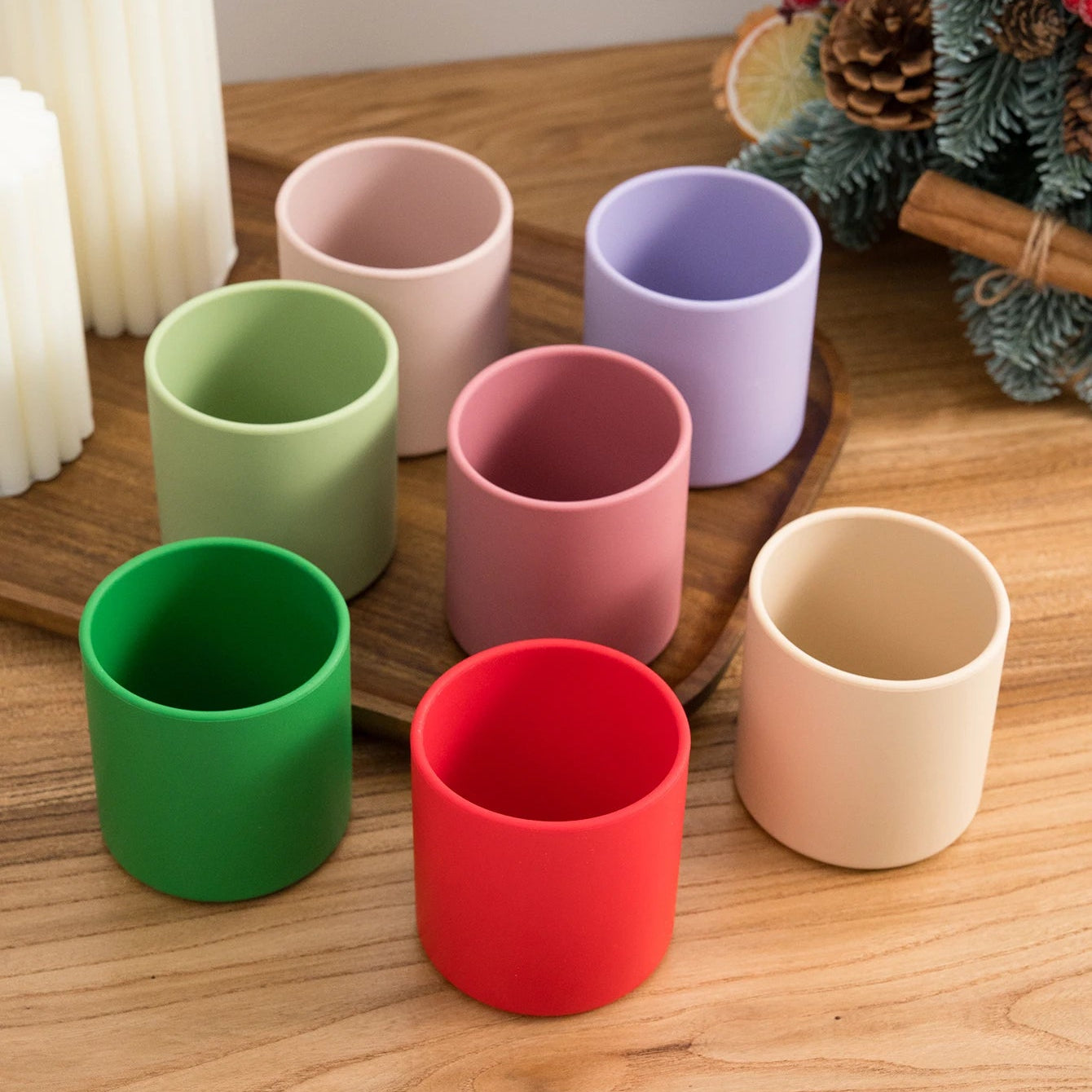 Red and green silicone training cups with pastel cups on a wooden tray