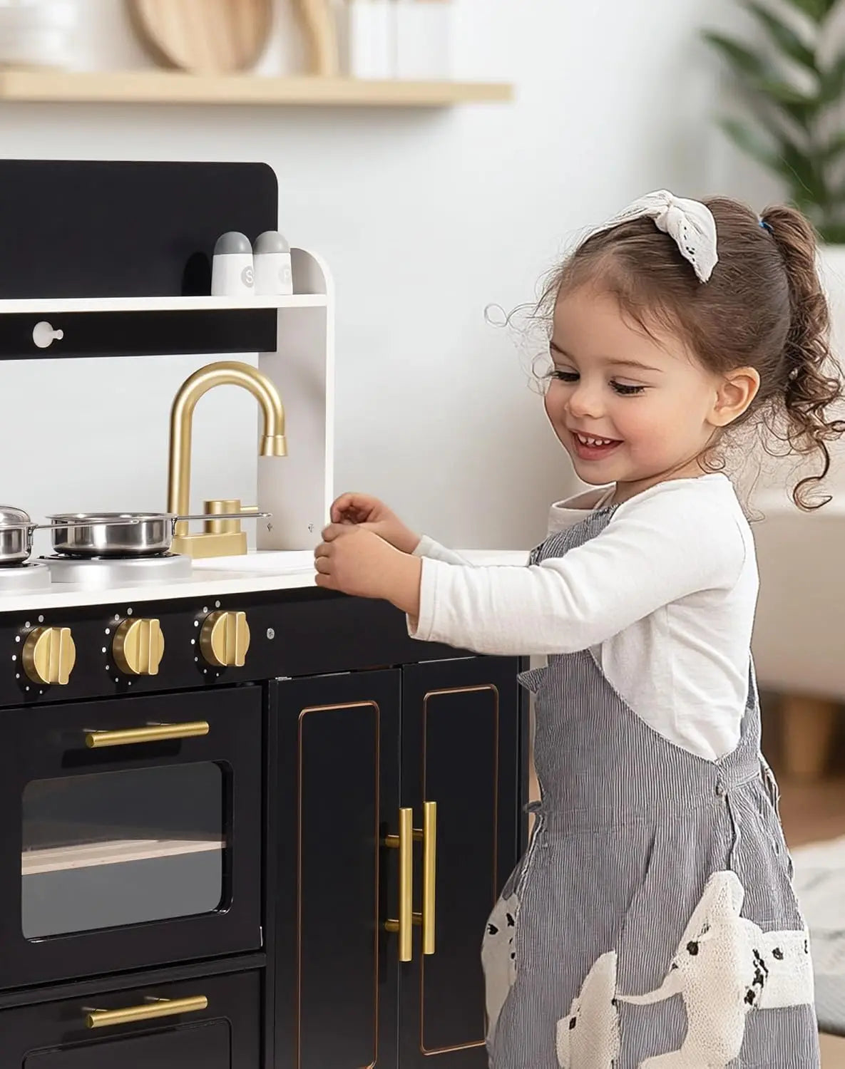 Child playing with a toy kitchen set in a home setting