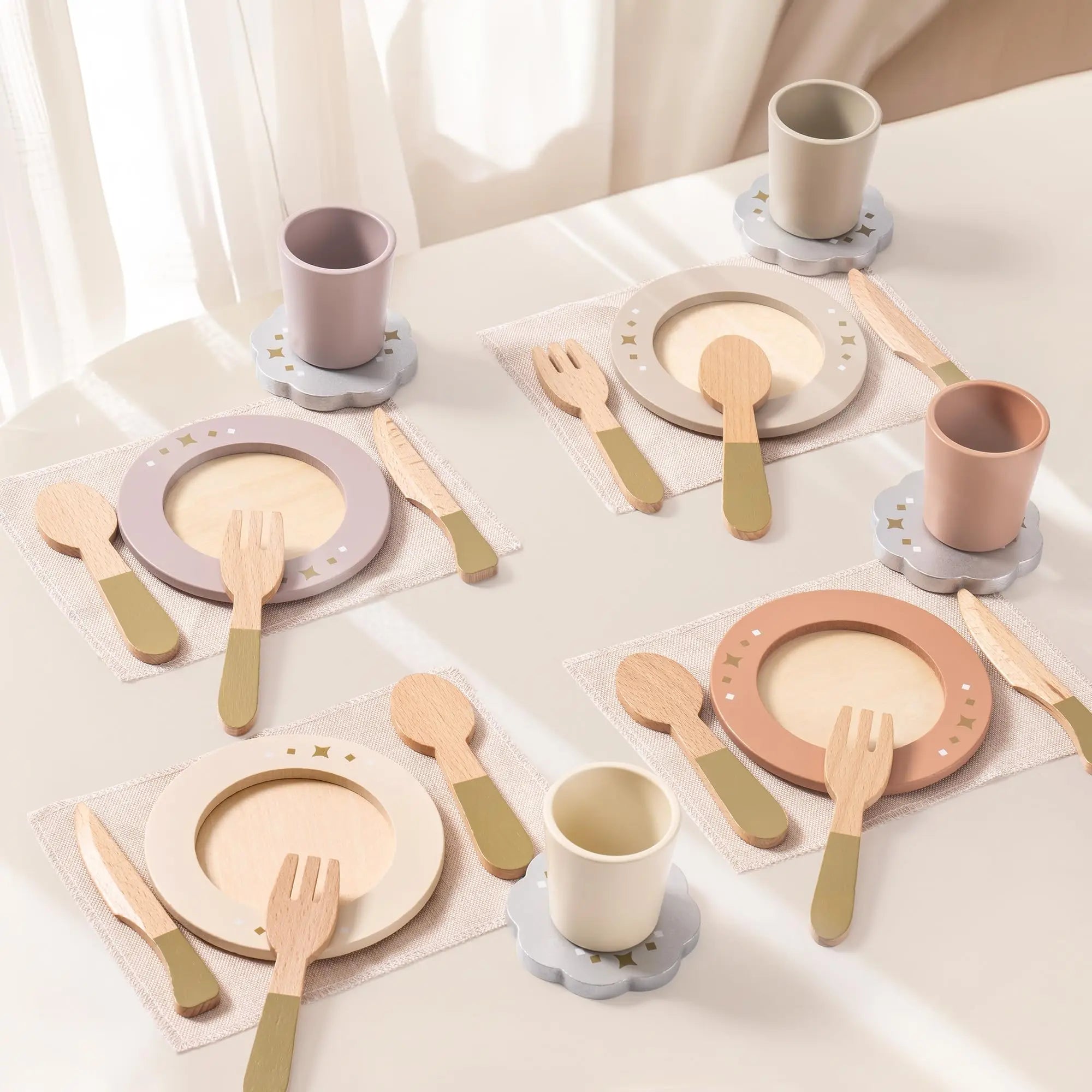 Children's tableware set with plates, cups, and cutlery on a light surface.