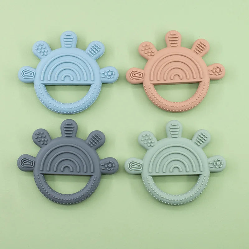 Four rainbow sun teethers in blue, peach, charcoal and sage